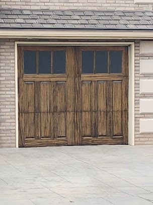 A wooden garage door is on the side of a brick building.