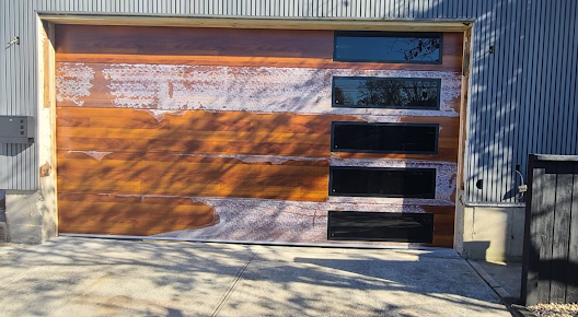 A wooden garage door is sitting in front of a metal building.