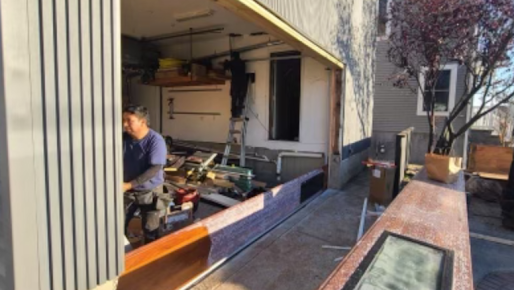 A man is working in a garage with the door open