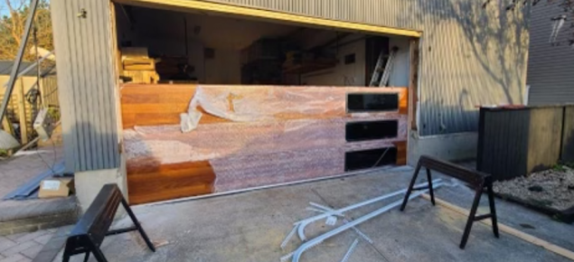 A wooden garage door is being installed in a garage.