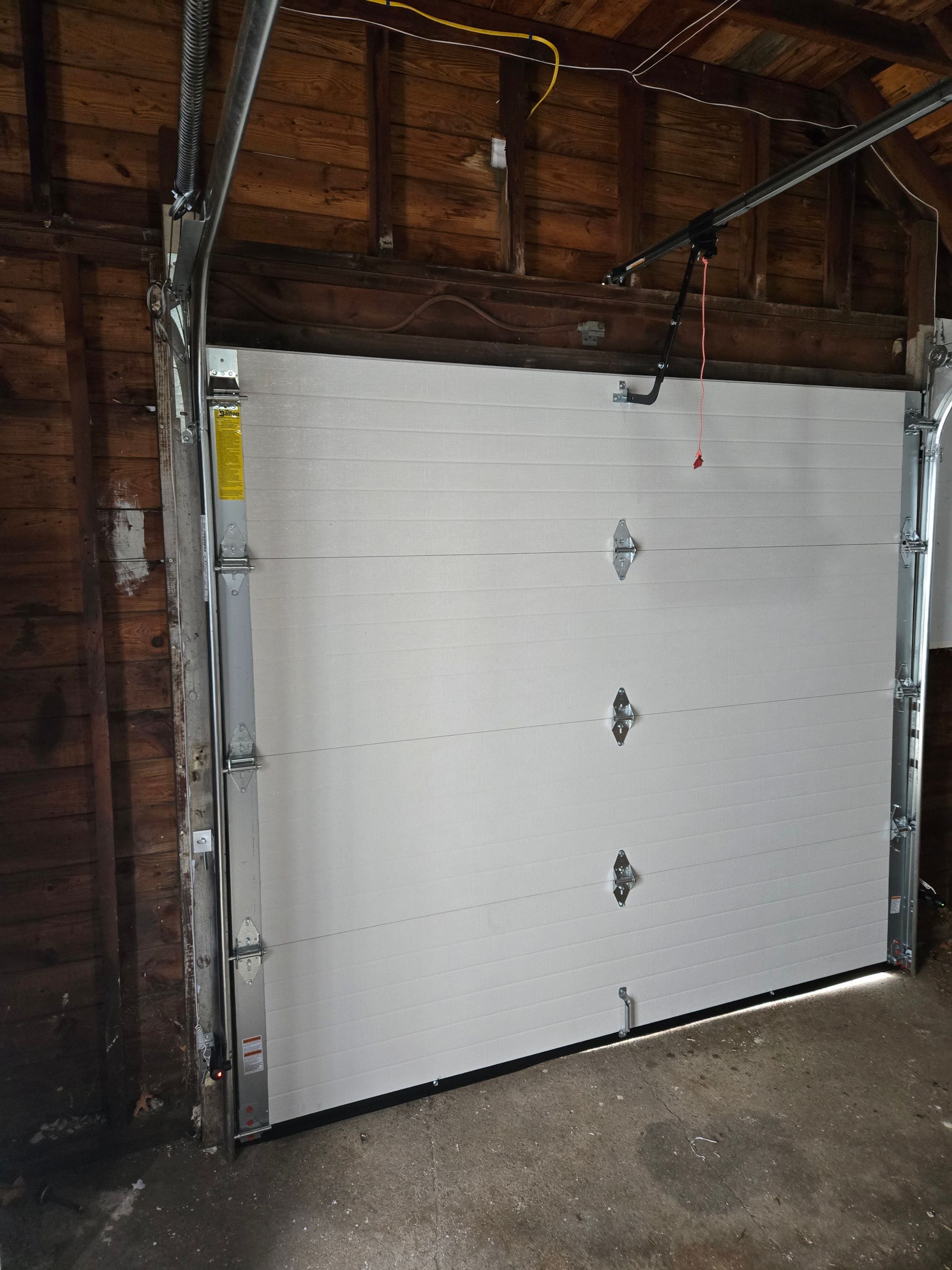 White garage door with metal framing, inside a garage.