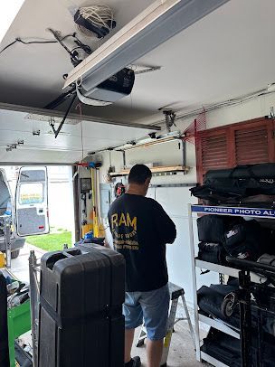 A man is standing in a garage working on a garage door opener.