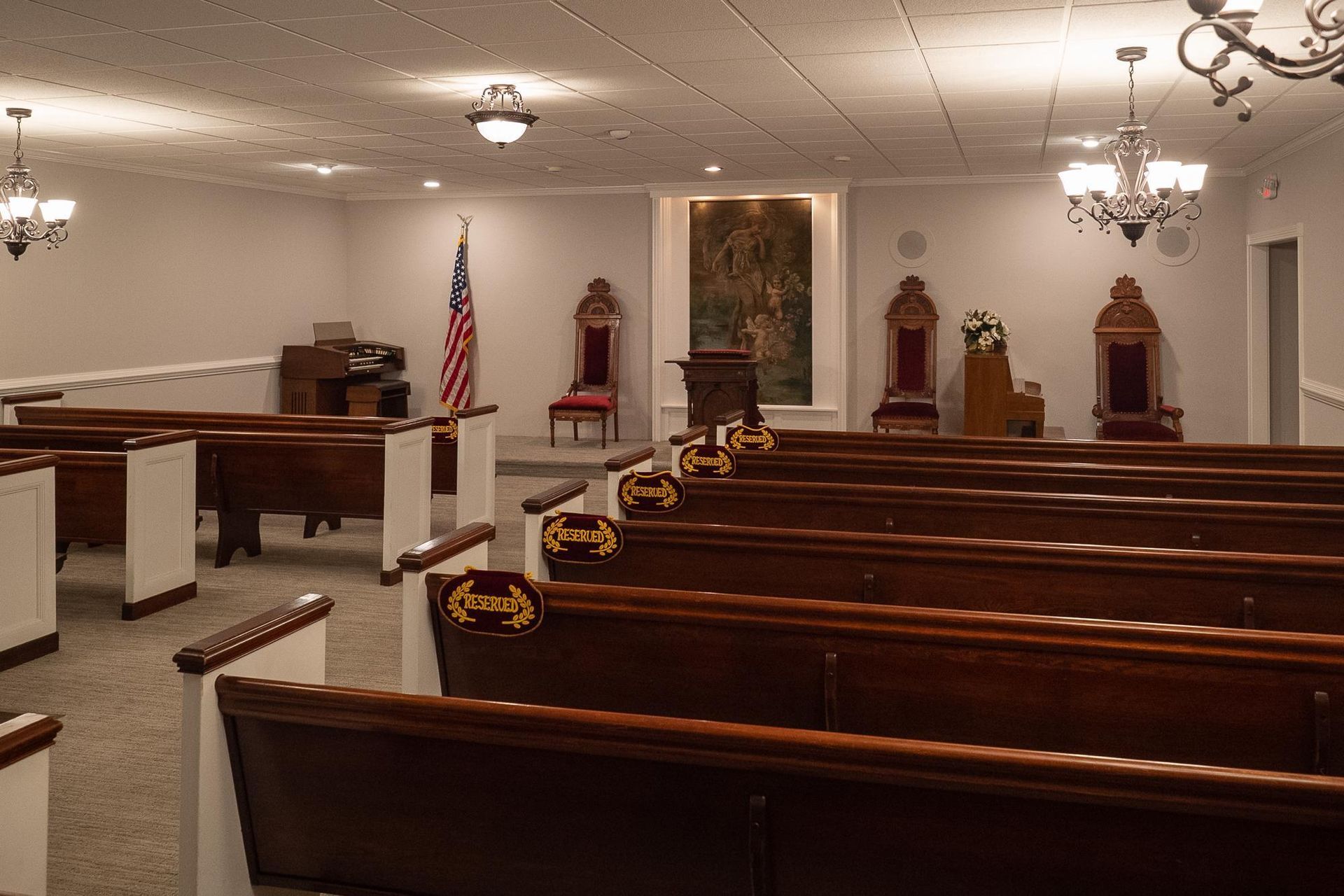 Empty church interior with wooden pews, altar, American flag, and chandeliers