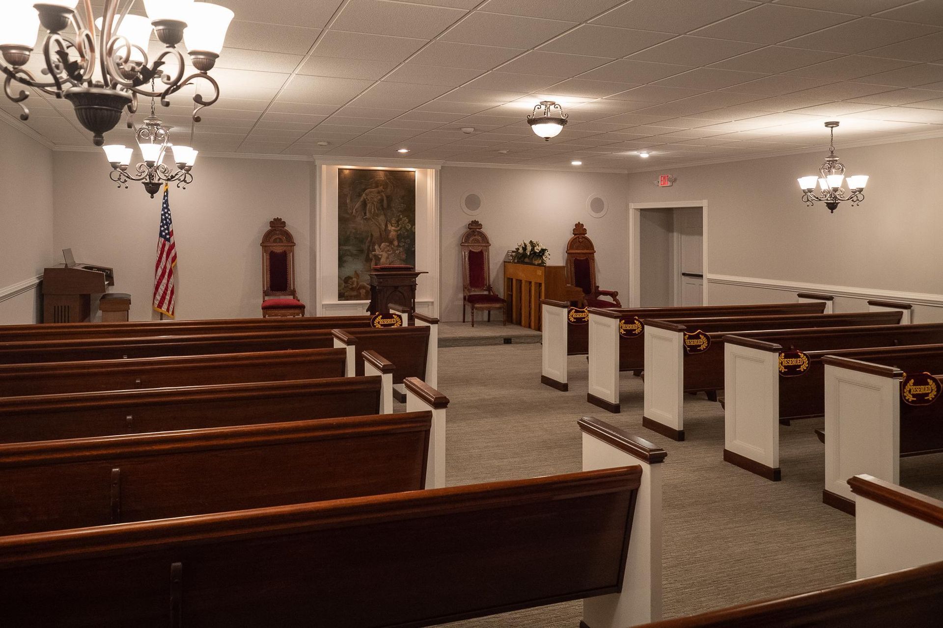 Interior of a church sanctuary with wooden pews, chandeliers, and an American flag by the altar