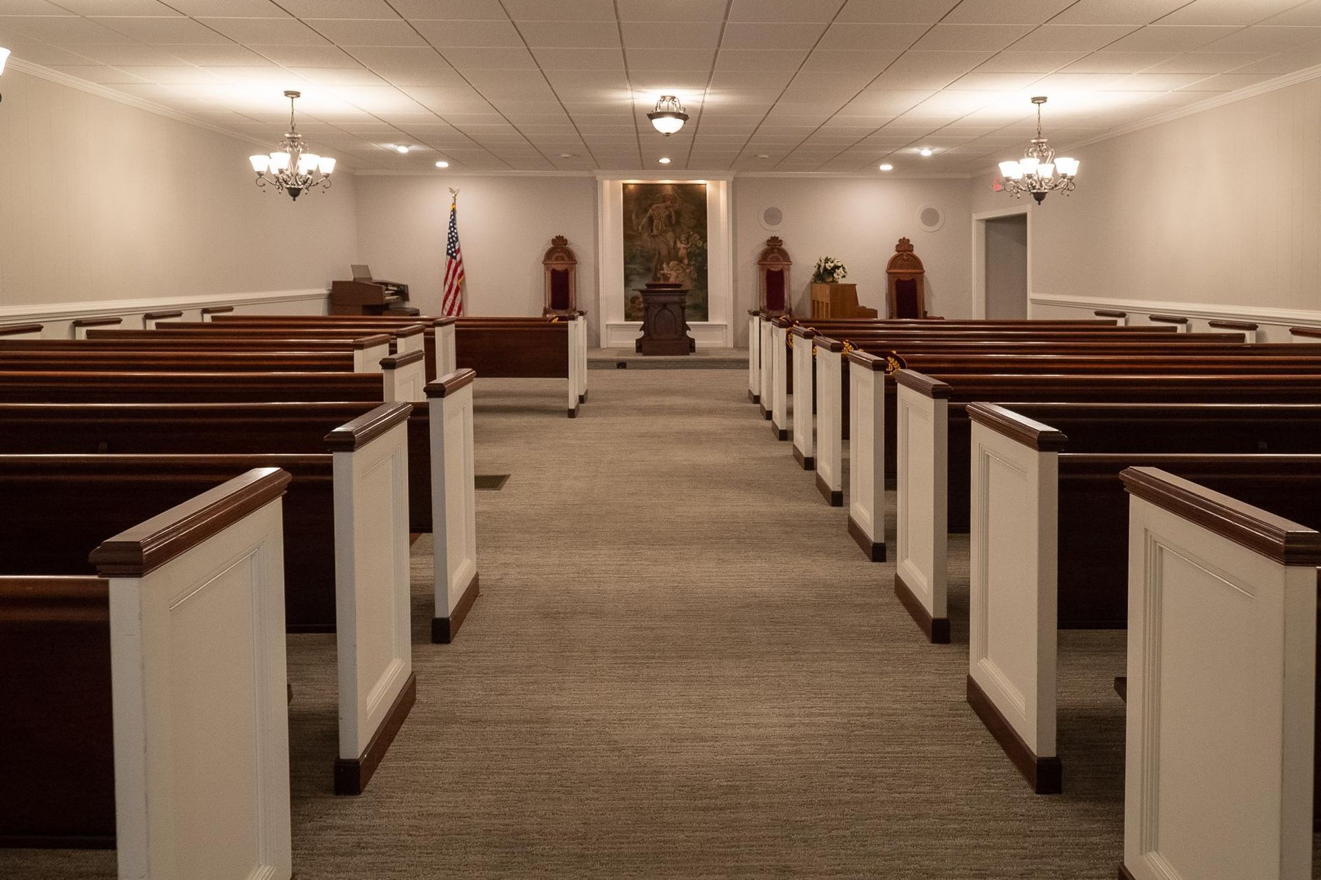 Church sanctuary with rows of wooden pews facing the altar and American flag