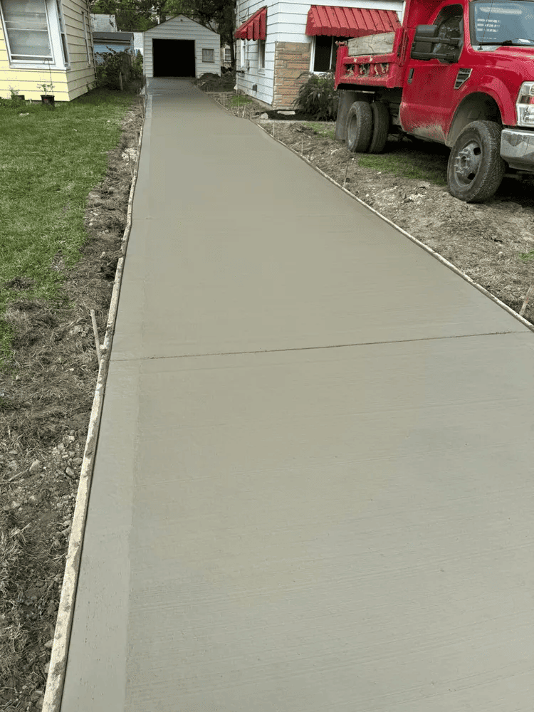 A red dump truck is parked on the side of a concrete driveway.