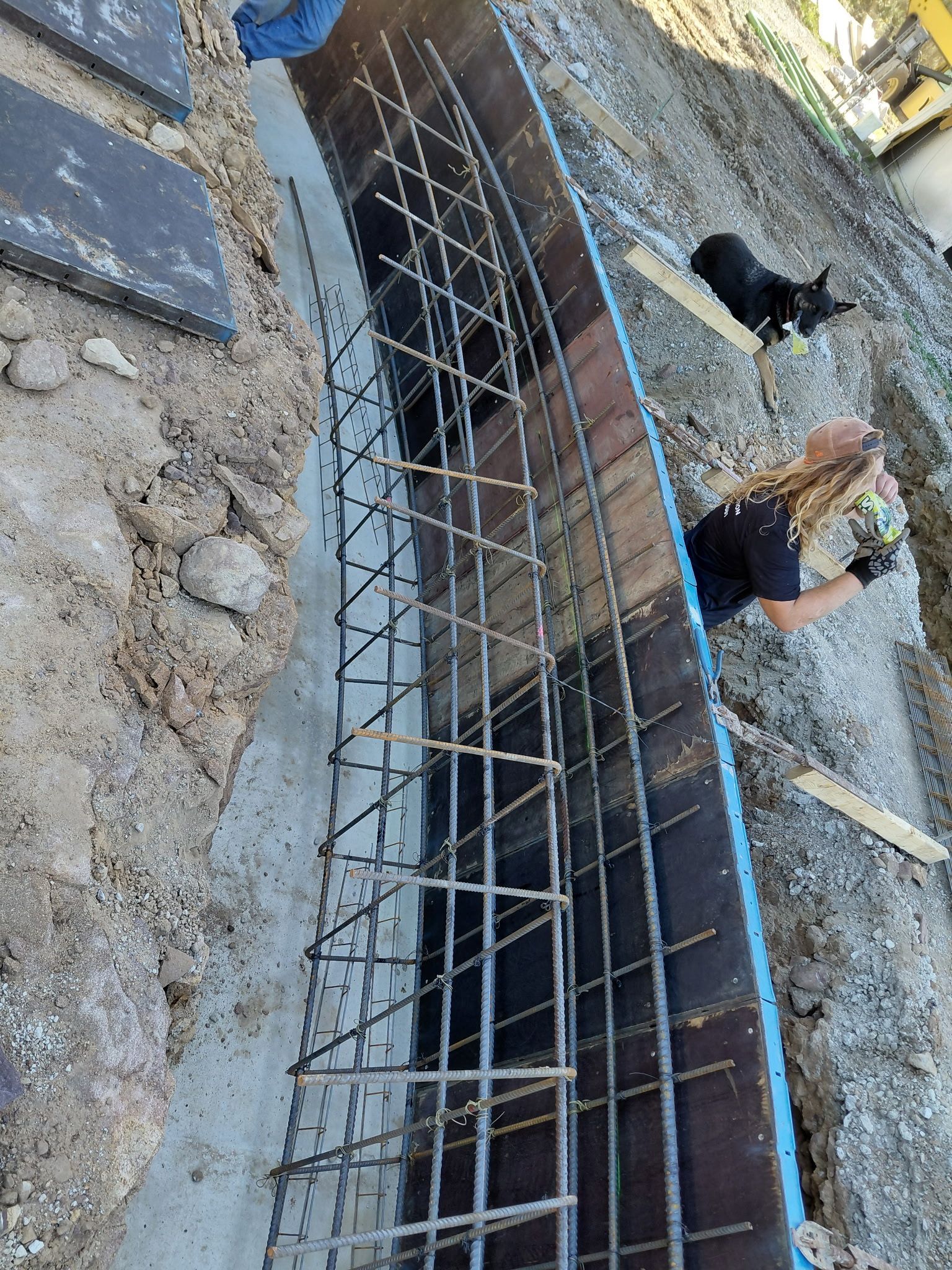 Construction rebar trench along a concrete slab, with workers’ boots visible nearby