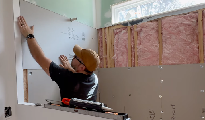 Contractor inspecting and installing drywall in the bathroom to prevent water damage, moisture, and mold or mildew growth.