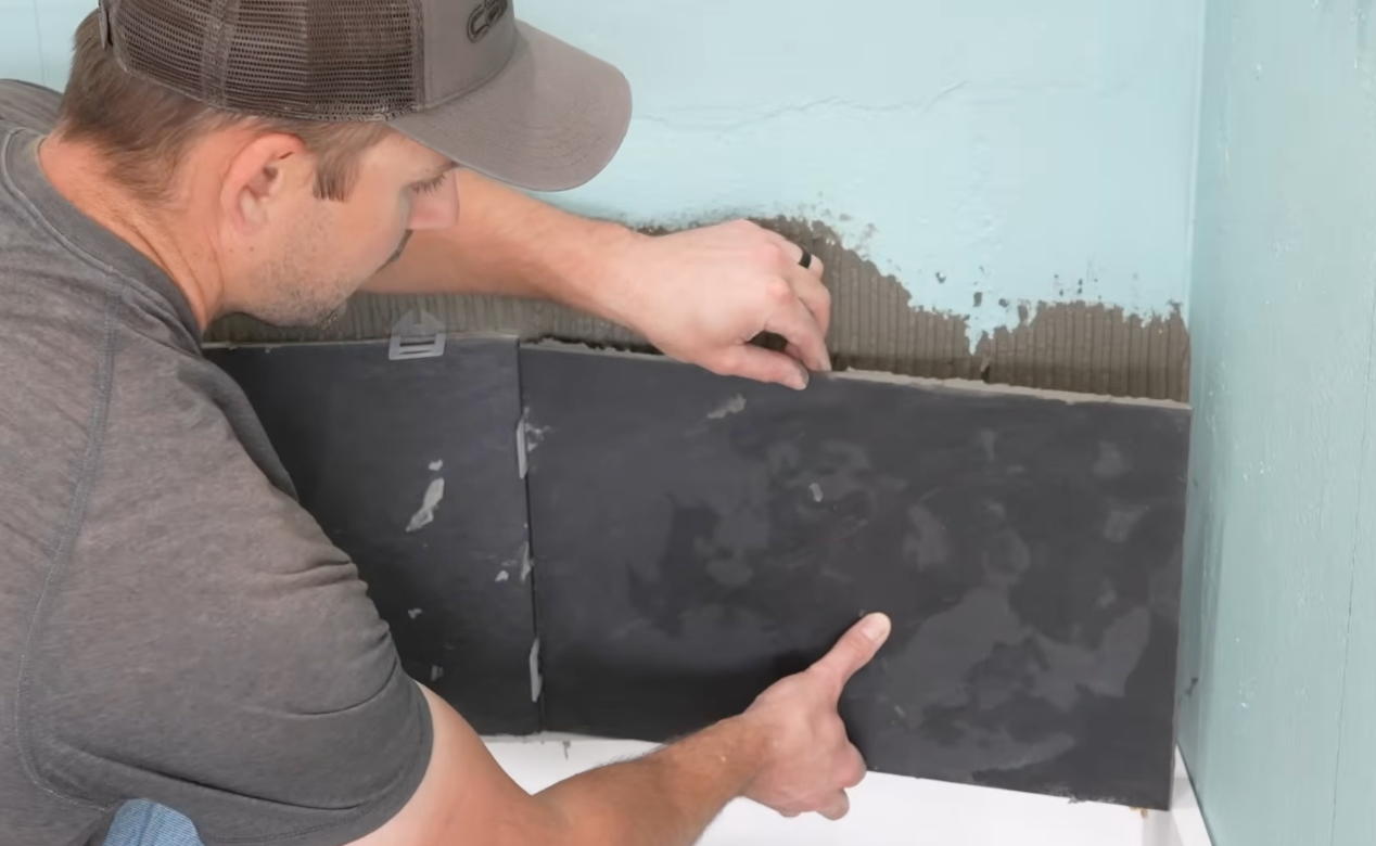 Contractor laying shower wall tiles carefully and meticulously to ensure proper alignment and sealing.