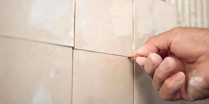 Contractor taking measurements and laying bathroom shower tiles to make sure tiles are aligned and spaced properly.