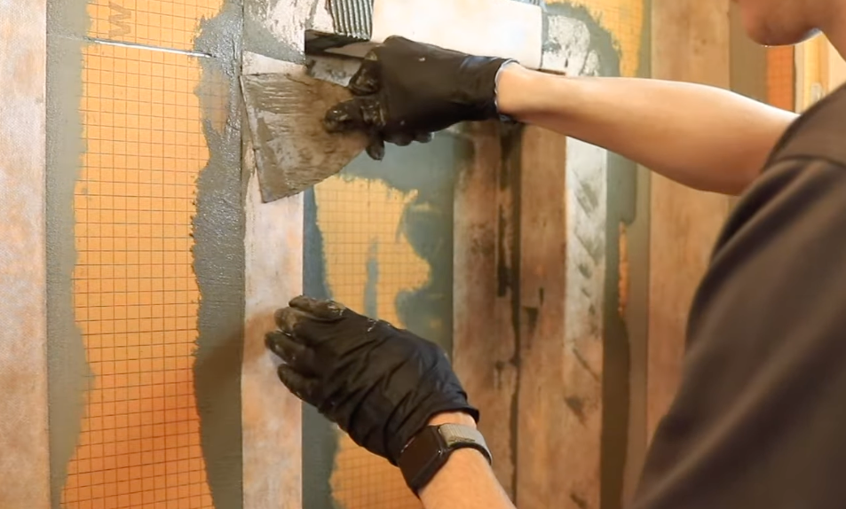 Contractor carefully installing waterproofing system for the bathroom to prevent water damage and mold growth.