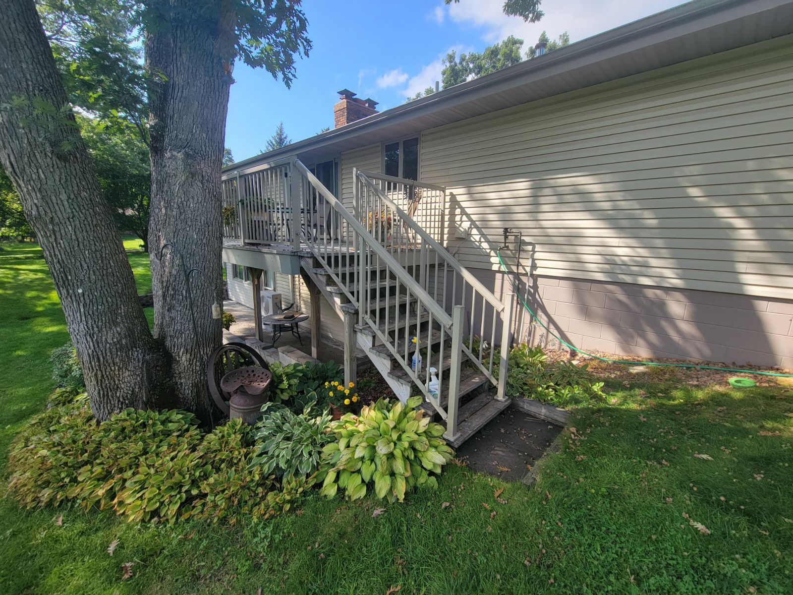 A house with stairs leading up to it and a tree in front of it.
