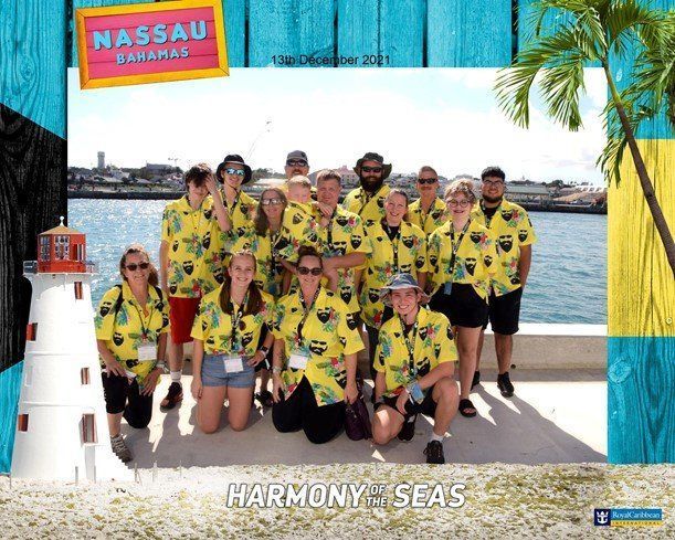 A group of people posing for a photo in front of a lighthouse in the bahamas