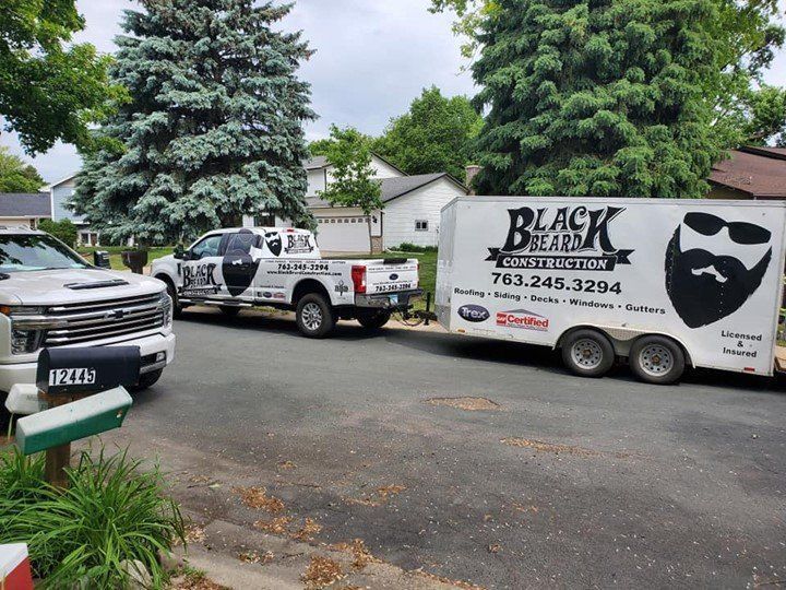 Two trucks and a trailer are parked on the side of the road.