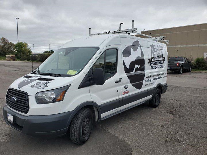 A white van is parked in a parking lot in front of a building.