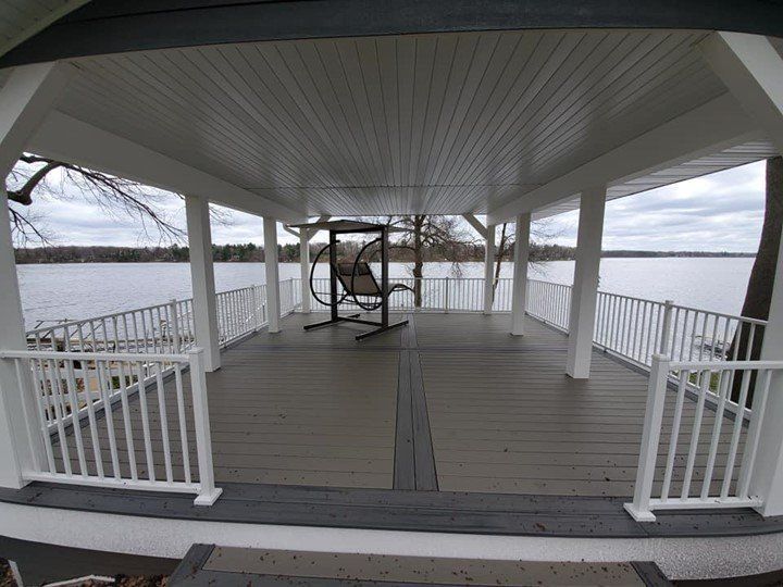 A porch with a swing and a view of a lake