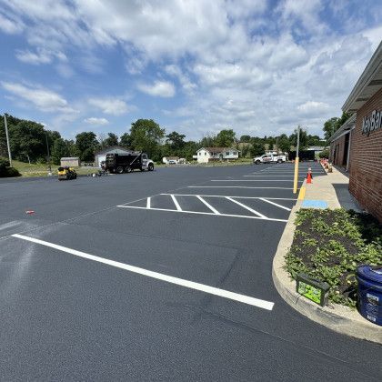Newly paved parking lot with white painted lines and landscaping. Blue sky with clouds.