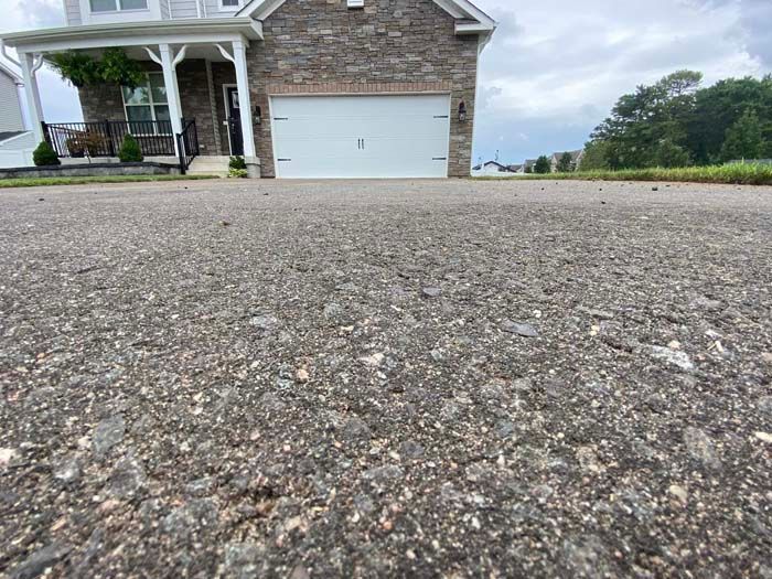 Close-up of asphalt driveway leading to a house with a white garage door.