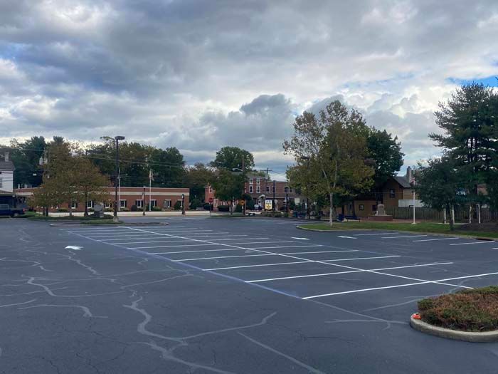 Empty parking lot with businesses in the background under a cloudy sky.
