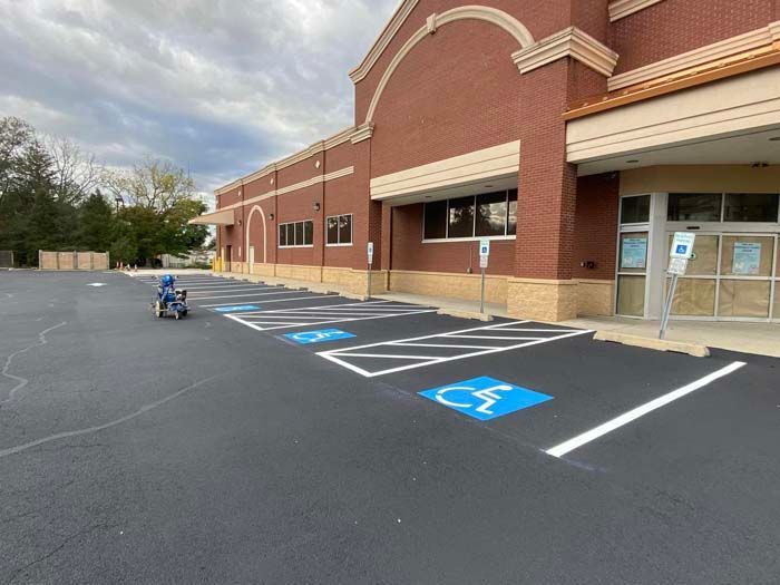 Exterior view of a building with fresh asphalt and marked handicap parking spaces.