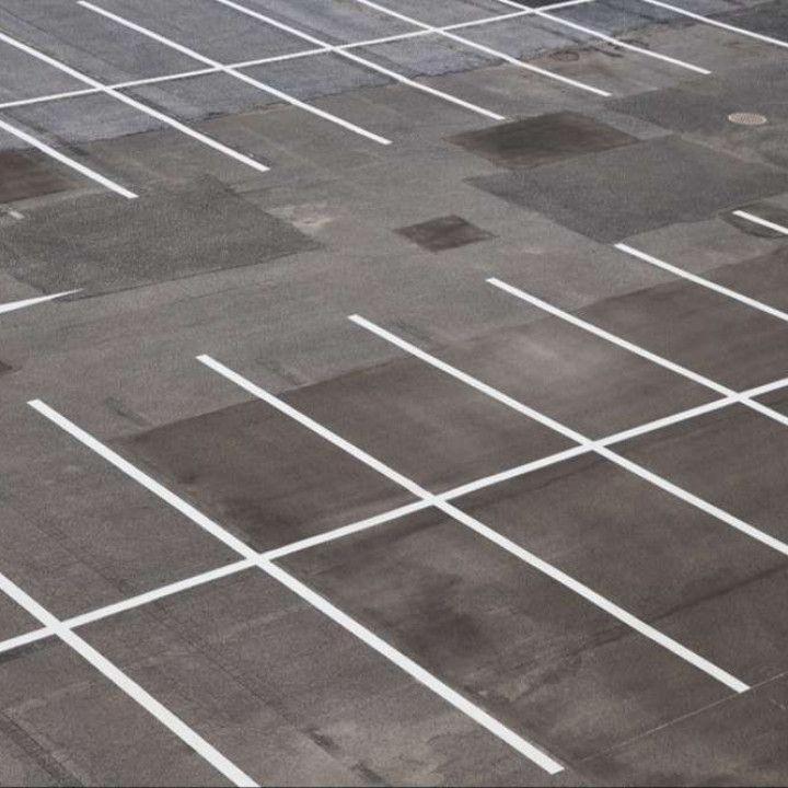 Empty parking lot with white painted lines on gray asphalt.