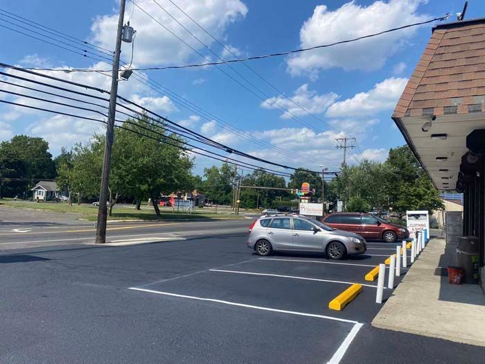 Parking lot with parked cars next to a building on a sunny day with utility poles in the background.