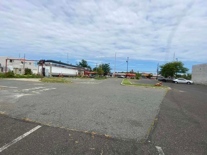 Empty parking lot with businesses in the background under a cloudy sky.
