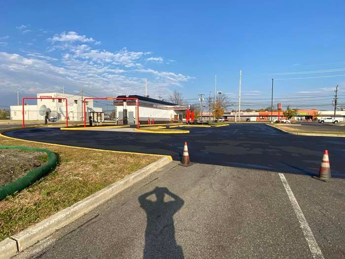 Car wash exterior on a sunny day with red framework. Shadow of person taking photo.