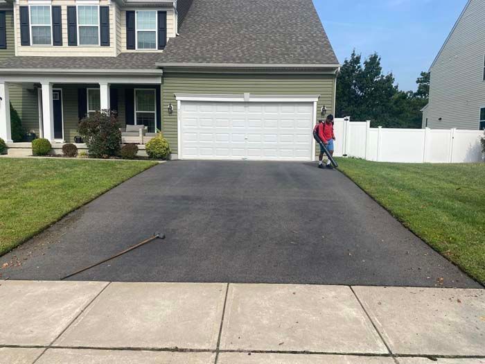 Driveway of a house being edged by a person with a power edger.
