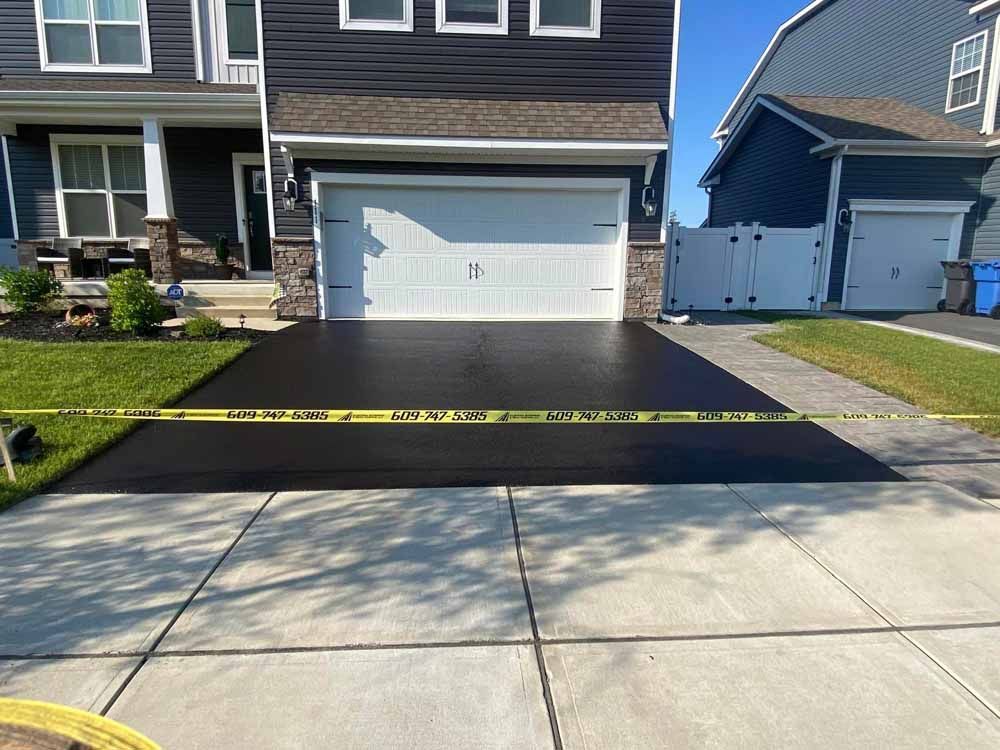 Freshly paved asphalt driveway blocked by yellow caution tape in front of a house.