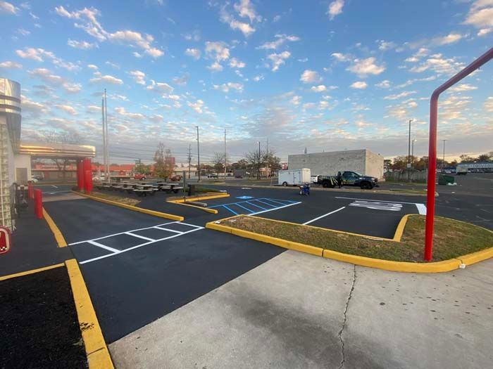 Exterior view of a newly paved parking lot with painted lines, handicap spots, and curb.