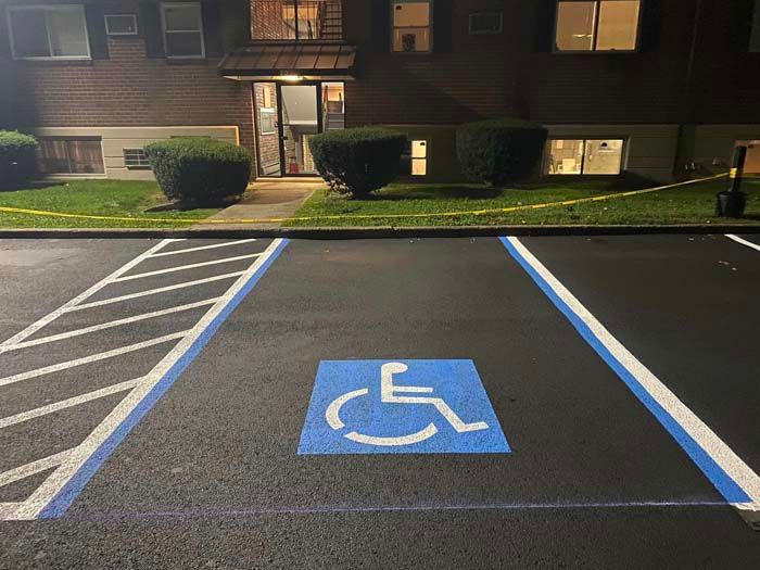 Handicapped parking space with wheelchair symbol painted in blue, in front of a building at night.