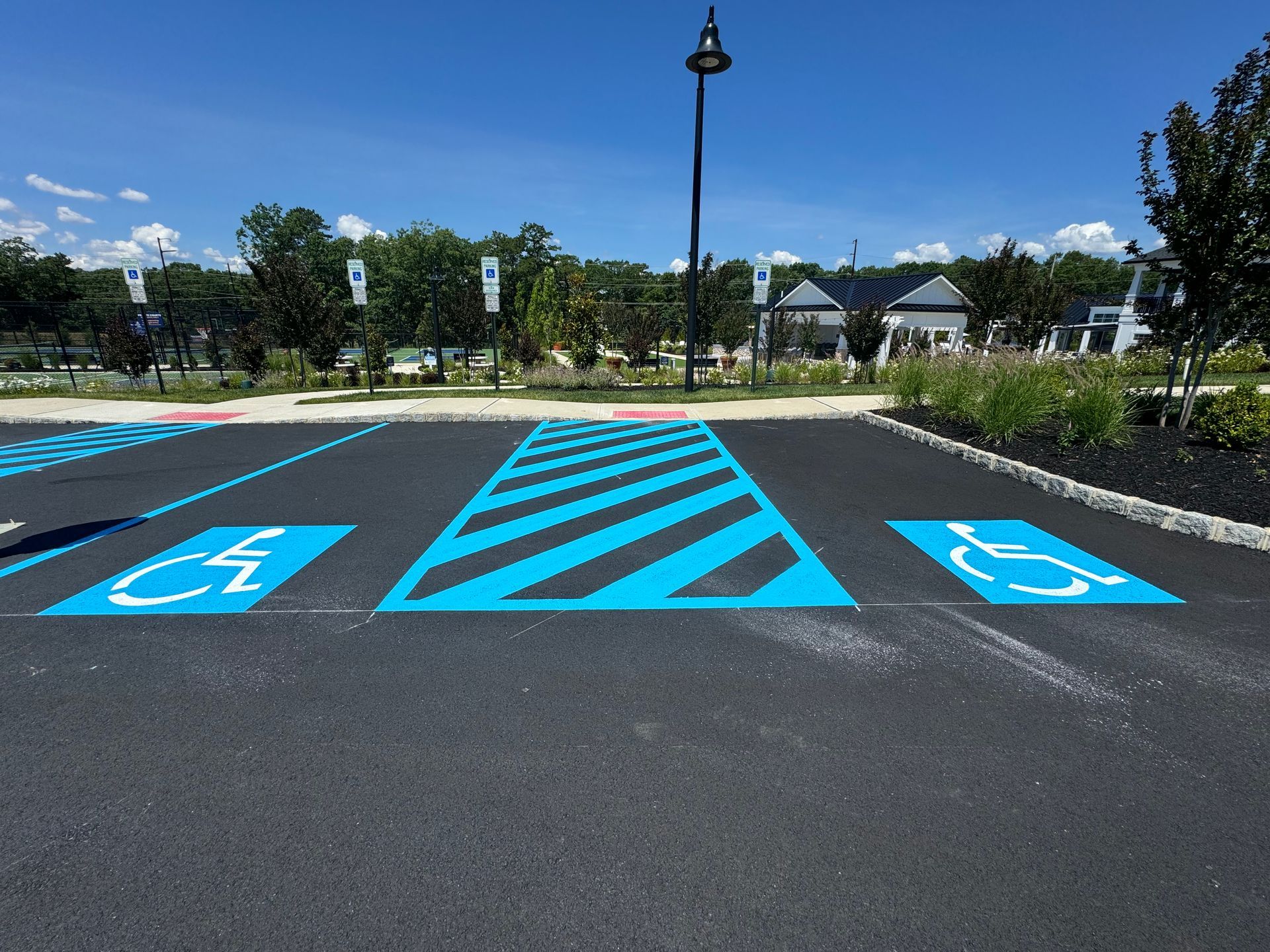 Parking lot with two blue handicap symbols and a striped access area painted on black asphalt.