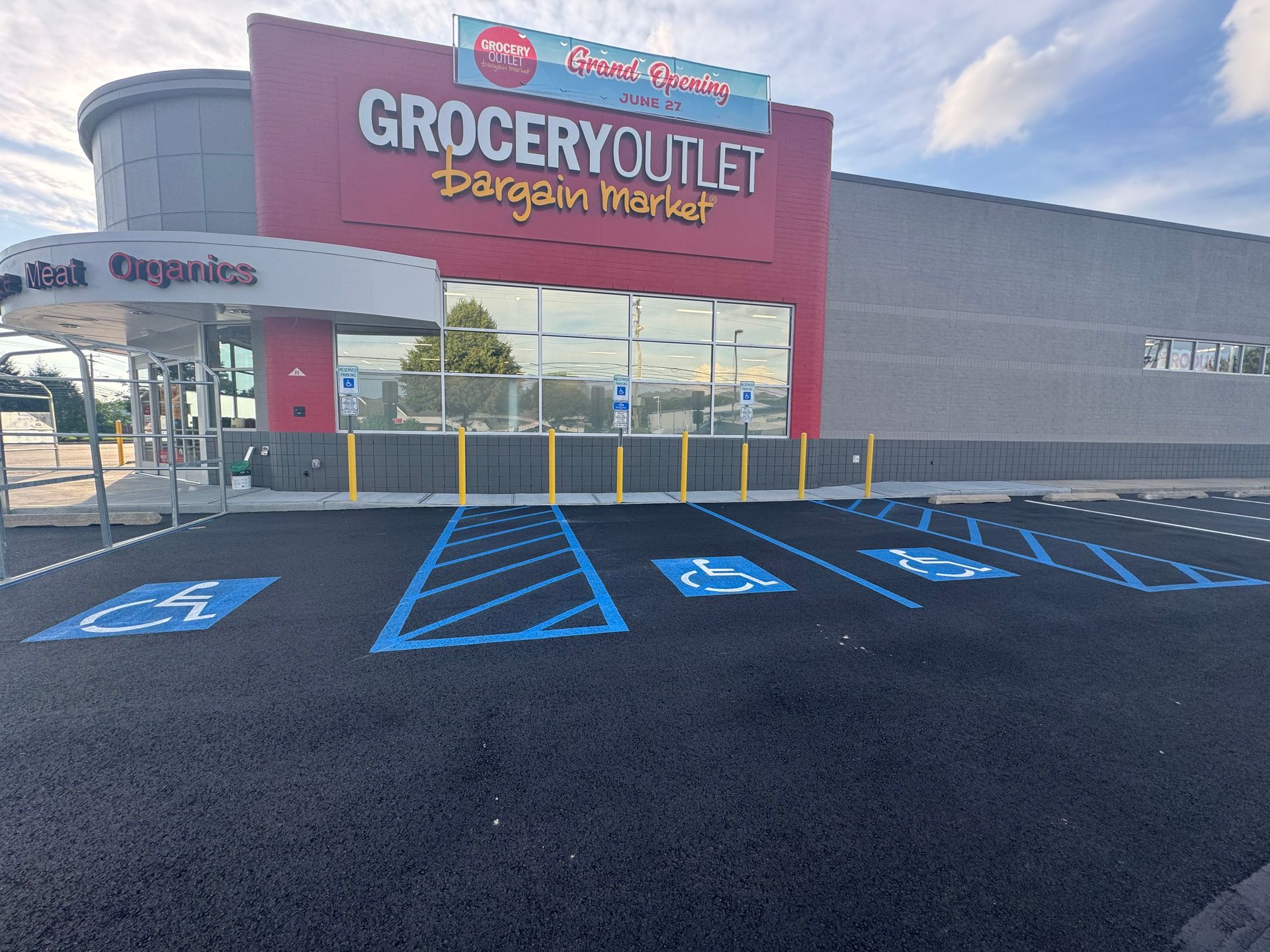 Exterior view of Grocery Outlet with accessible parking spaces marked in blue paint.
