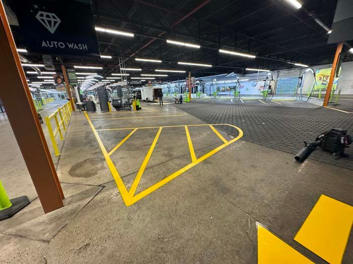 Interior of an auto wash facility with yellow lines marking a vehicle path.