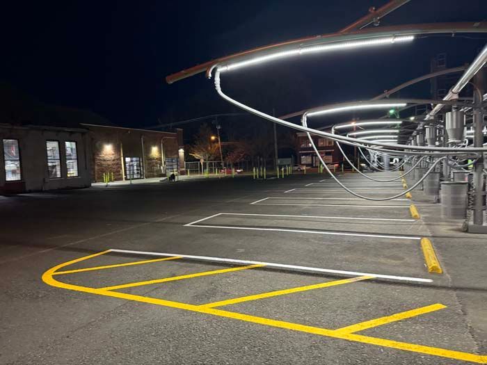 Empty car wash at night with bright overhead lights and yellow parking lines.