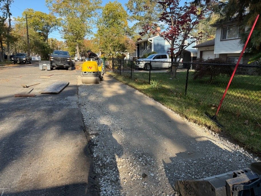 Damaged residential street with a yellow car, patched asphalt, and houses along the sidewalk