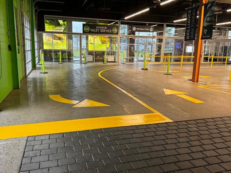 Entrance to a valet service with yellow directional arrows and glass doors.