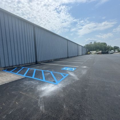 Parking lot with blue handicap space markings and a long gray building.