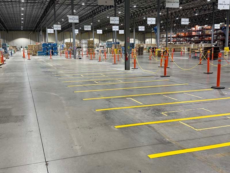 Large warehouse floor with yellow painted work areas and safety bollards.