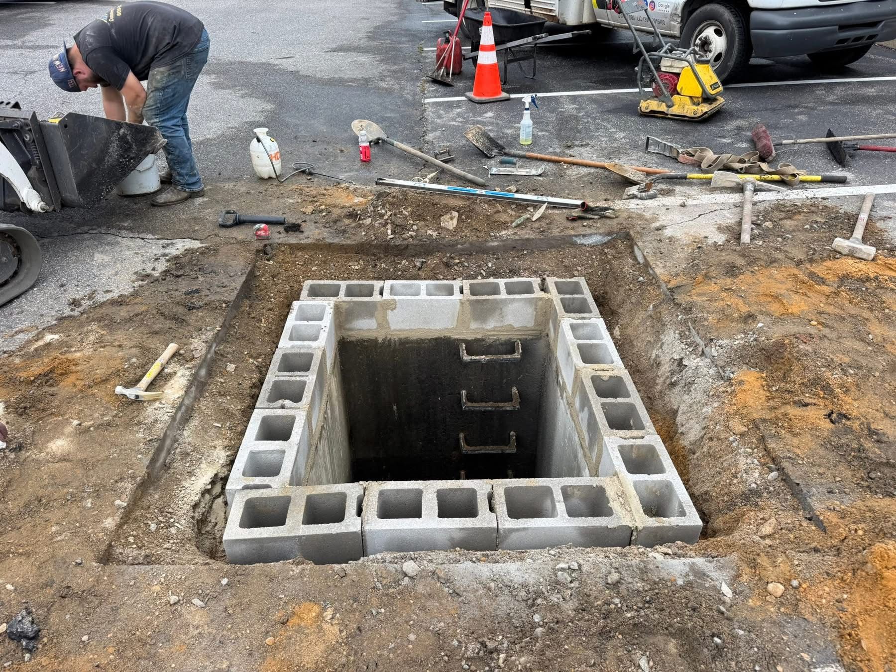 Open utility box at a road construction site with workers and equipment nearby