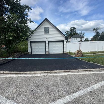 Two-car white garage with black asphalt driveway on a sunny day.