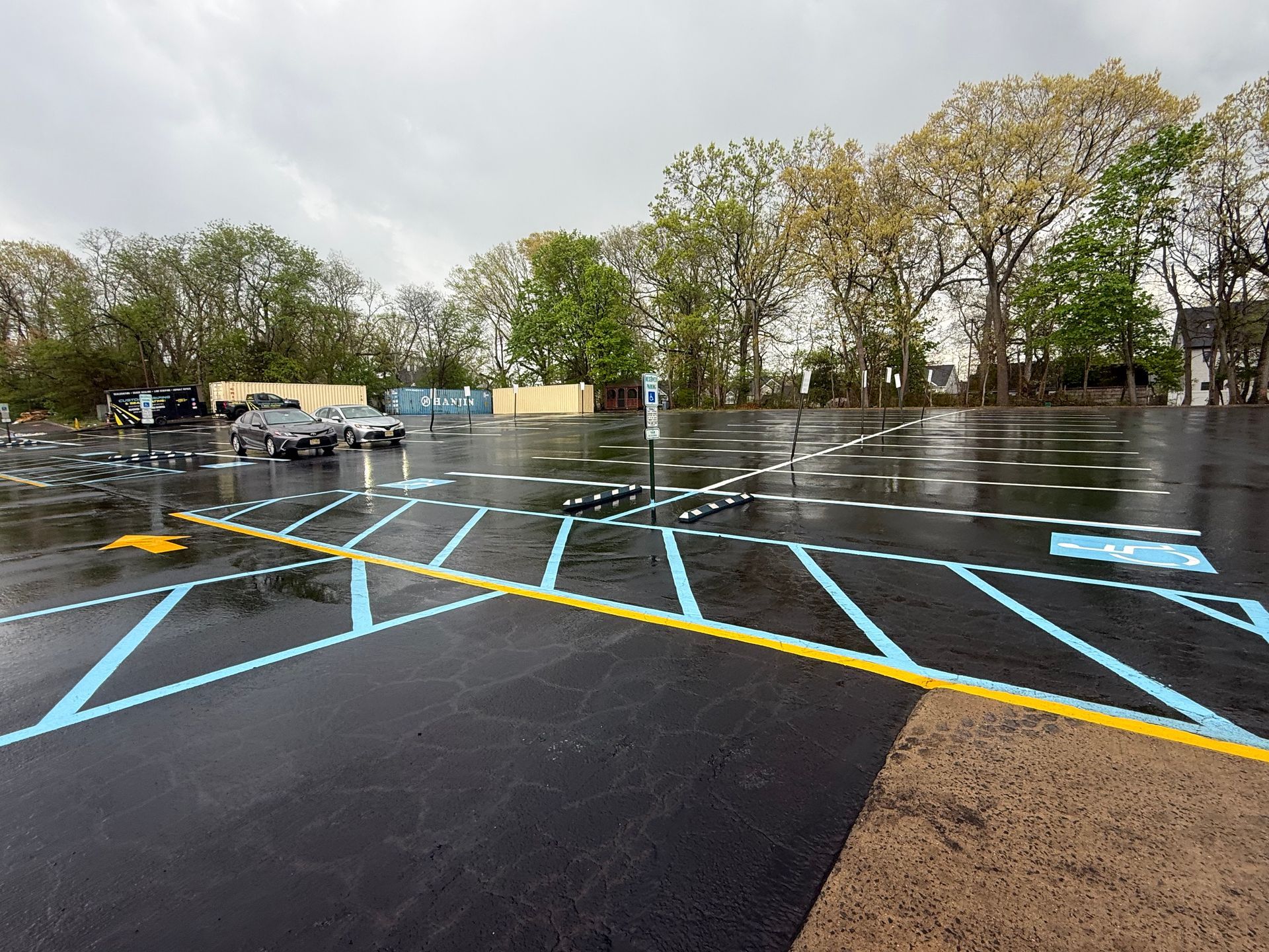 Empty wet parking lot with blue and yellow painted lines under cloudy sky
