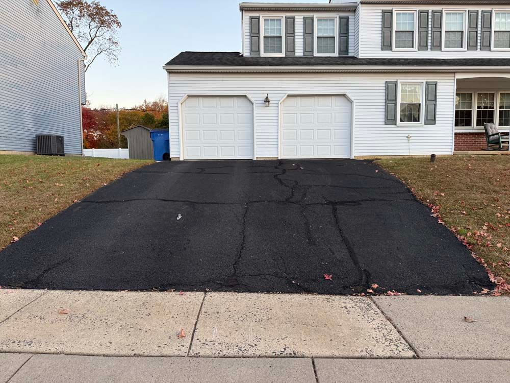 Suburban house with white garage and a cracked black asphalt driveway in front