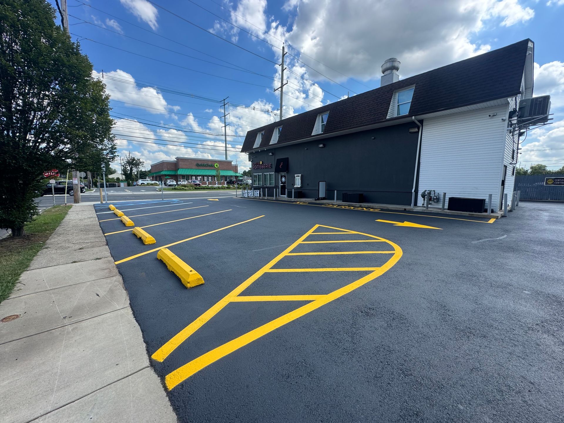 Blacktop parking lot with yellow painted lines and bumpers next to a building.