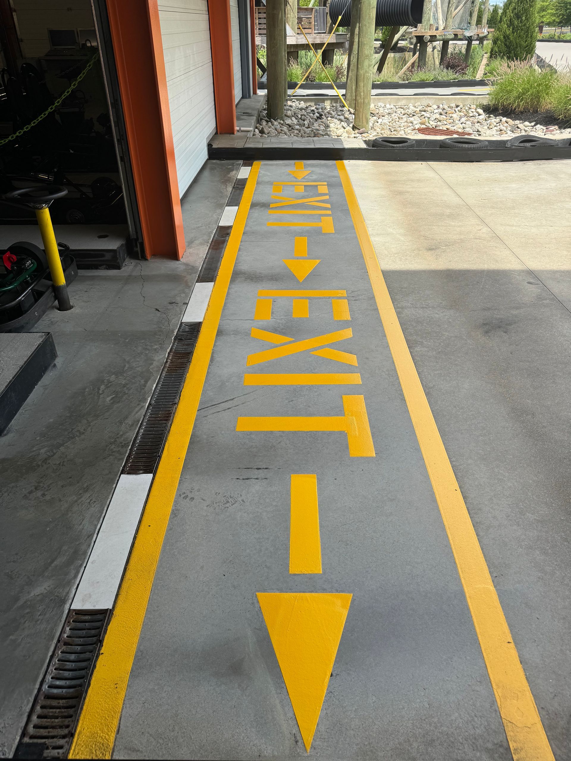 Yellow painted EXIT lane with arrow on gray concrete.