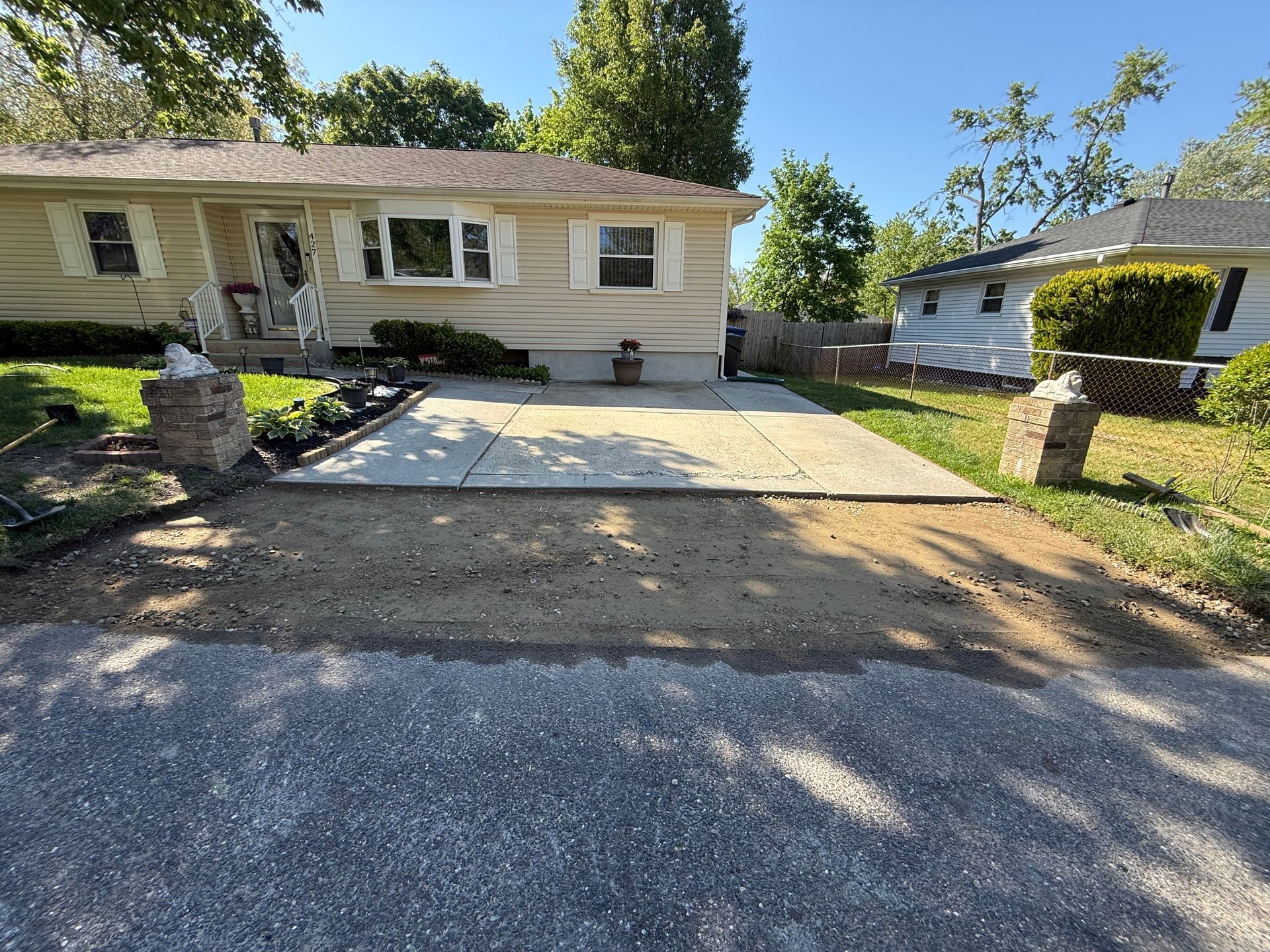Single-story house with a freshly poured concrete driveway and front yard on a sunny day