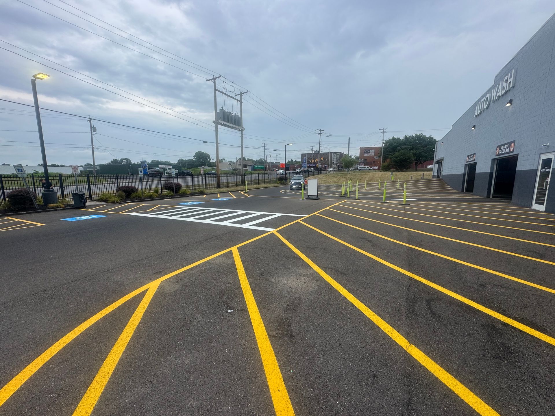 Asphalt parking lot with yellow painted lines. Building with loading docks on right, overcast sky.