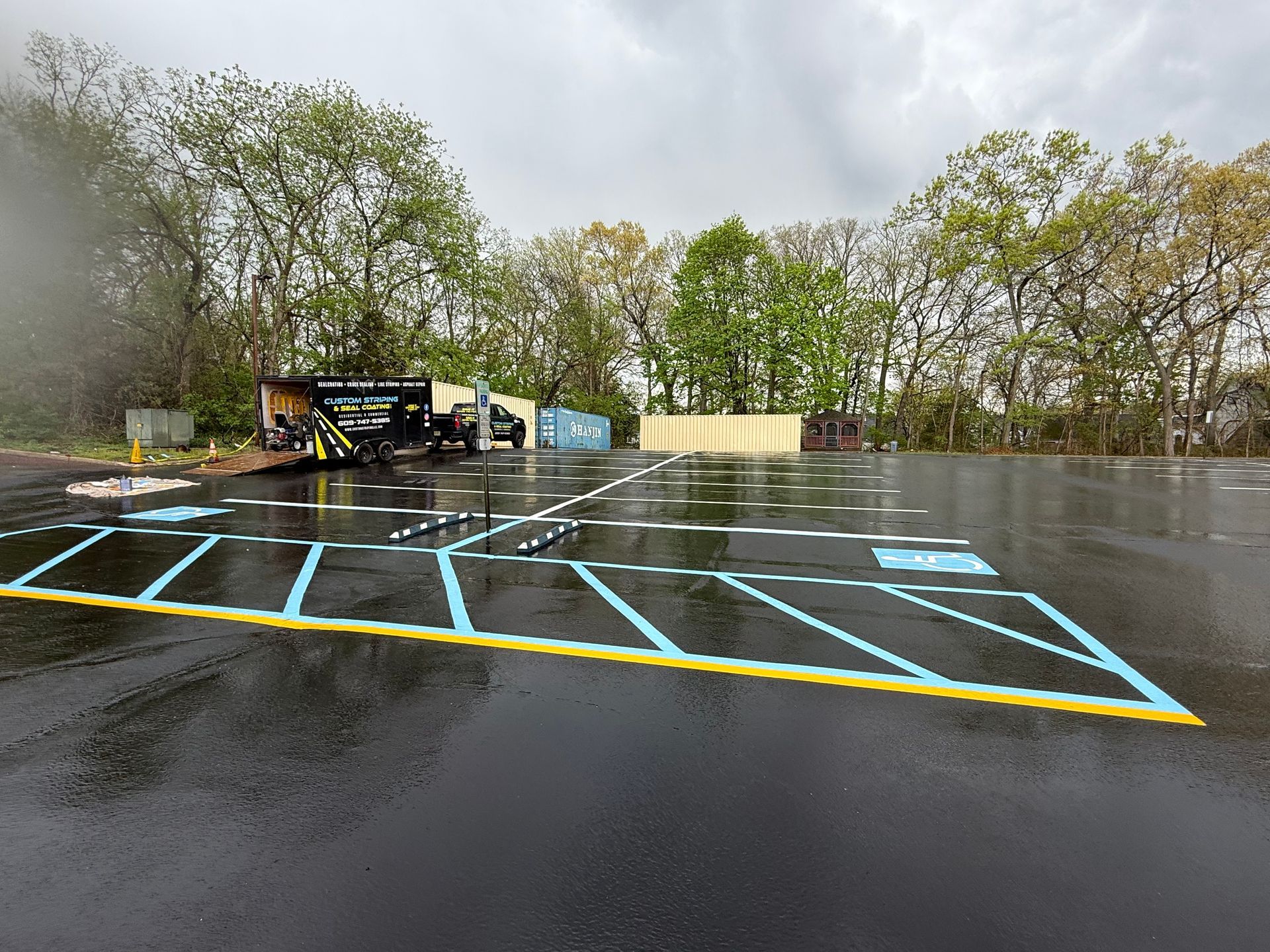 Wet parking lot with blue and yellow painted parking lines under overcast skies.
