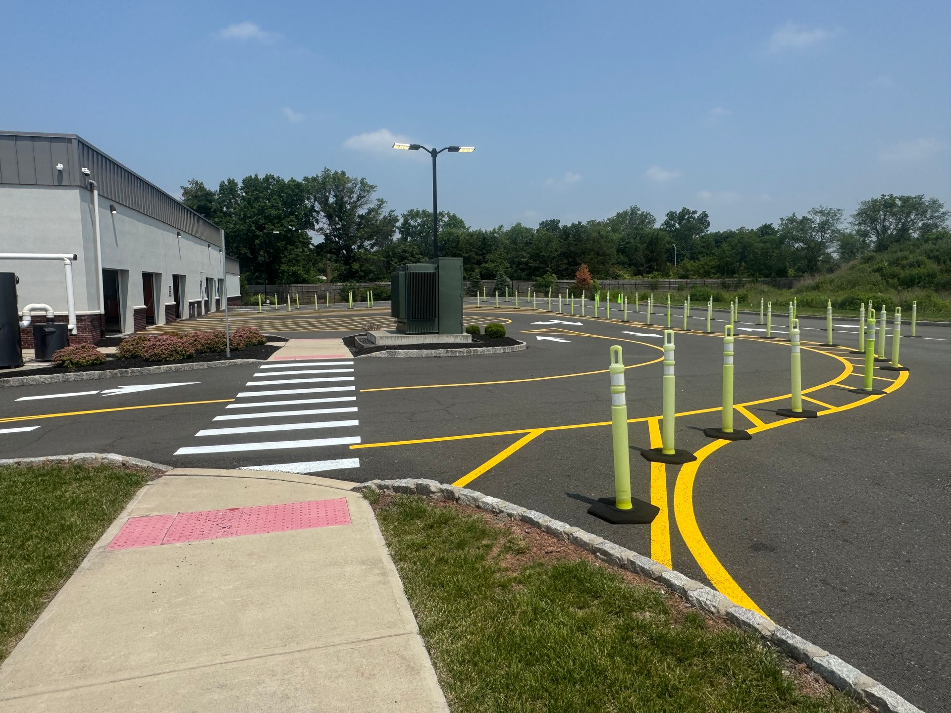 Driveway with crosswalk, yellow lane markings, and green bollards.